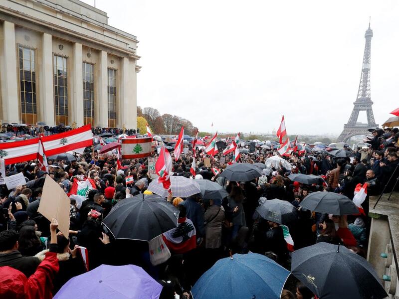 People hold signs and wave Lebanon national flags as they take part in a demonstration to support Lebanese protests, on October 20, 2019 in front of the Eiffel Tower at the Trocadero in Paris. (FRANCOIS GUILLOT / AFP)