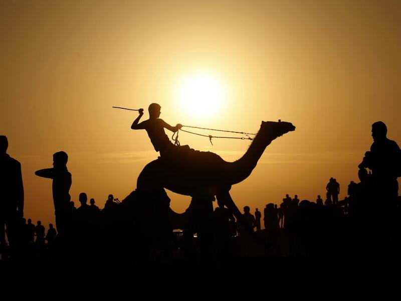 A Palestinian jockey is silhouetted as he competes in a local camel race held at the destroyed Gaza airport, in Rafah in the southern Gaza Strip on October 20, 2019. SAID KHATIB / AFP