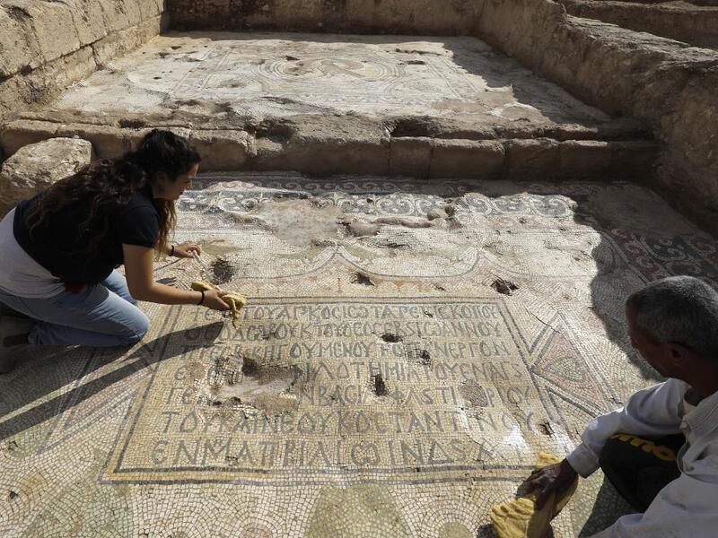 Timnah Goloubin (L), an archaeologist with the Israel Antiquities Authority, shows on October 23, 2019 a mosaic inscription in ancient Greek mentioning a donation received from Emperor Tiberius II, in the Israeli town of Bet Shemesh. The magnificent 1500-year-old church, decorated with spectacular mosaic floors and Greek inscriptions, was discovered during a three-year excavation near a residential area. MENAHEM KAHANA / afp