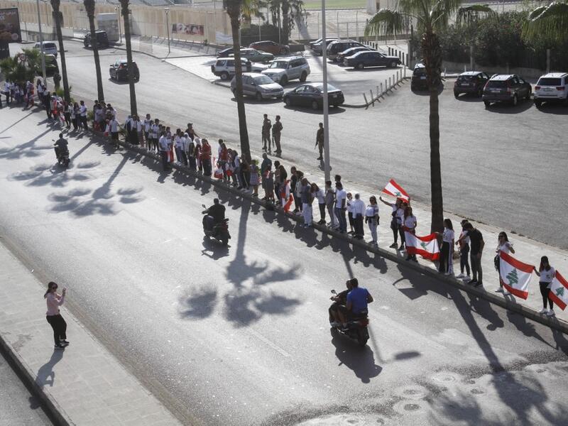 Lebanese protesters hold hands to form a human chain along the coast from north to south as a symbol of unity, during ongoing anti-government demonstrations in the southern Lebanese port city of Sidon on October 27, 2019. Mahmoud ZAYYAT / AFP
