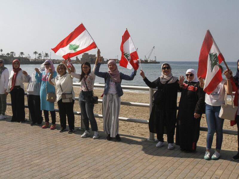Lebanese protesters hold hands to form a human chain along the coast from north to south as a symbol of unity, during ongoing anti-government demonstrations in the southern Lebanese port city of Sidon on October 27, 2019. Mahmoud ZAYYAT / AFP