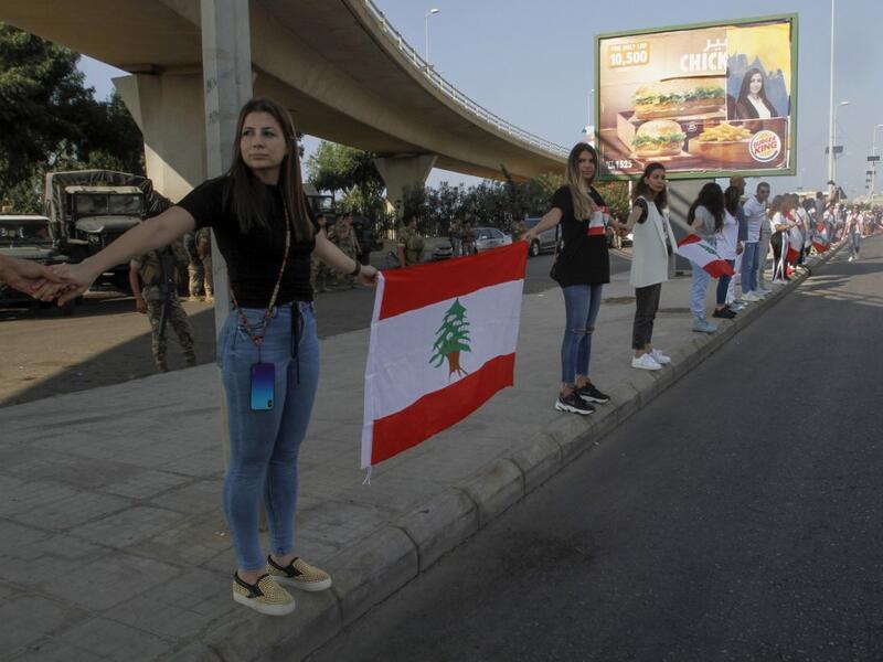 Lebanese protesters hold hands to form a human chain along the coast from north to south as a symbol of unity, during ongoing anti-government demonstrations in the southern Lebanese port city of Sidon on October 27, 2019. Mahmoud ZAYYAT / AFP