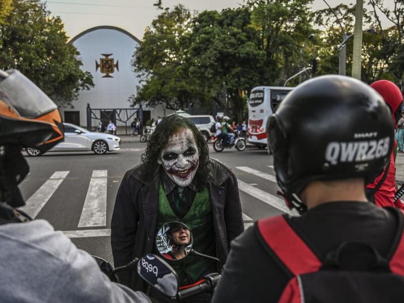 Venezuelan migrant Johnny Tales, who makes a living imitating the comicbook and film character "The Joker", performs at a traffic light in Medellin, on October 29, 2019. JOAQUIN SARMIENTO / AFP