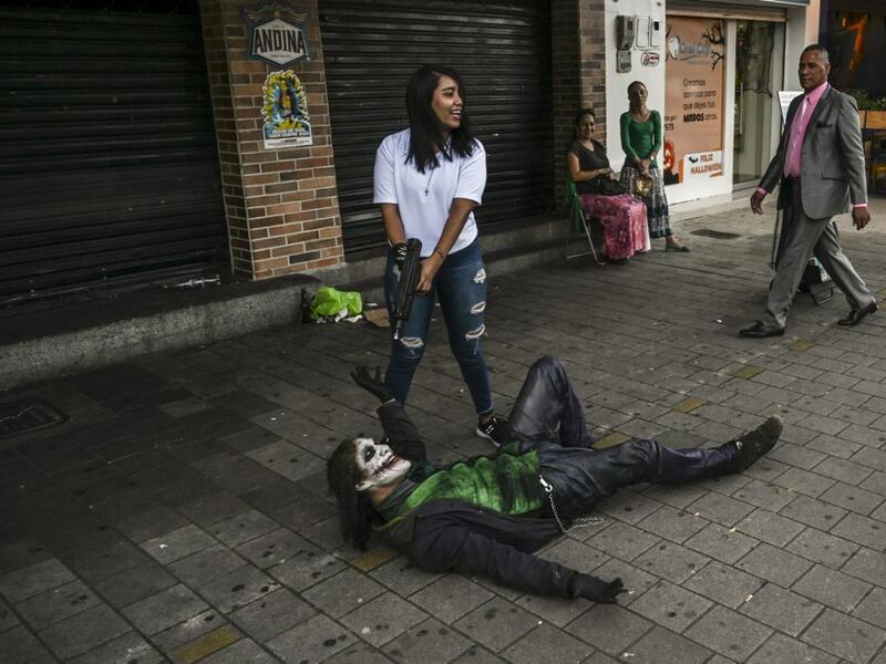 Venezuelan migrant Johnny Tales (R), who makes a living imitating the comicbook and film character "The Joker", poses for a photograph in a street of Medellin, on October 29, 2019. JOAQUIN SARMIENTO / AFP