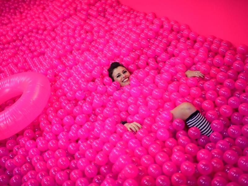 A woman smiles, while lying in a ball bath, at the "Supercandy Pop-Up Museum Vol. 2" in Cologne, western Germany on November 1, 2019. It is an interactive museum and offers a photo backdrop for social media at 25 stations. INA FASSBENDER / AFP