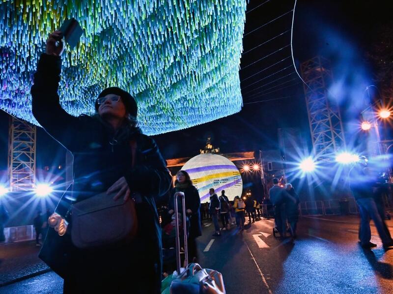 Visitors walk under installation "Visions in Motion" by artist Patrick Shearn and his studio Poetic Kinetics in front of Berlin's landmark the Brandenburg Gate on November 4, 2019 in Berlin. As Germany and it's capital Berlin will celebrate the 30th anniversary of the Fall of the Wall, the skynet made of 30,000 ribbons that bear aloft the wishes, hopes, and memories of 30,000 people today will be on display from November 4 to 10, 2019. Tobias SCHWARZ / AFP