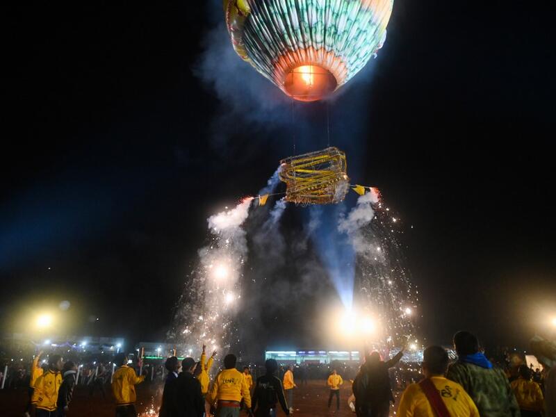 This picture taken on November 4, 2019 shows participants releasing a hot-air balloon attached with fireworks during the Tazaungdaing Lighting Festival at Taunggyi in Myanmar's northeastern Shan State. Brightly coloured balloons with hundreds of homemade fireworks woven into their frames are sent soaring into the night sky, showering down cascades of sparks onto adoring crowds in the annual Taunggyi fire balloon festival. Ye Aung THU / AFP