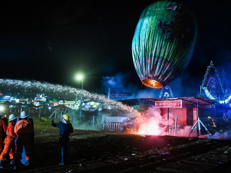This picture taken on November 4, 2019 shows firefighters at work after a fireworks-laden hot-air balloon ignited before the balloon was at a sufficient height during during the Tazaungdaing Lighting Festival at Taunggyi in Myanmar's northeastern Shan State. Brightly coloured balloons with hundreds of homemade fireworks woven into their frames are sent soaring into the night sky, showering down cascades of sparks onto adoring crowds in the annual Taunggyi fire balloon festival. Ye Aung THU / AFP