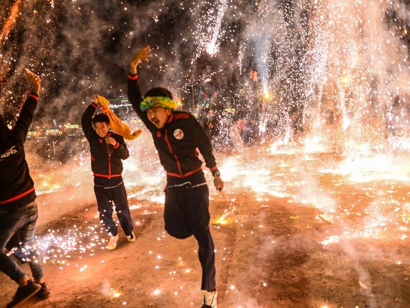 This picture taken on November 5, 2019 shows participants celebrating as fireworks explode after they released a hot-air balloon attached with fireworks during the Tazaungdaing Lighting Festival at Taunggyi in Myanmar's northeastern Shan State. Brightly coloured balloons with hundreds of homemade fireworks woven into their frames are sent soaring into the night sky, showering down cascades of sparks onto adoring crowds in the annual Taunggyi fire balloon festival. Ye Aung THU / AFP