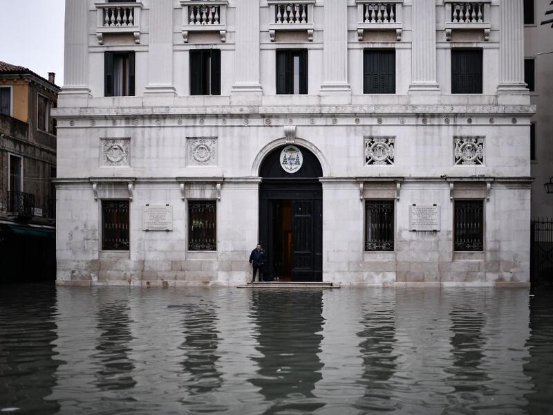 A man stands by the entrance of the Palazzo Patriarcale on the flooded Piazza dei Leoncini square after an exceptional overnight "Alta Acqua" high tide water level, early on November 13, 2019 in Venice. Powerful rainstorms hit Italy on November 12, with the worst affected areas in the south and Venice, where there was widespread flooding. Within a cyclone that threatens the country, exceptional high water were rising in Venice, with the sirocco winds blowing northwards from the Adriatic sea against the lago