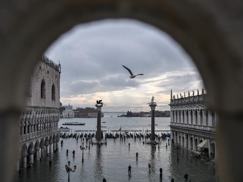 A general view shows the Doge's Palace (L) overlooking the flooded St. Mark's Square, the Lion of St. Mark winged bronze statue (Rear L), gondolas and the Venetian lagoon in the distance after an exceptional overnight "Alta Acqua" high tide water level, on November 13, 2019 in Venice. Venice was hit by the highest tide in more than 50 years late November 12, with tourists wading through flooded streets to seek shelter as a fierce wind whipped up waves in St. Mark's Square. Marco Bertorello / AFP