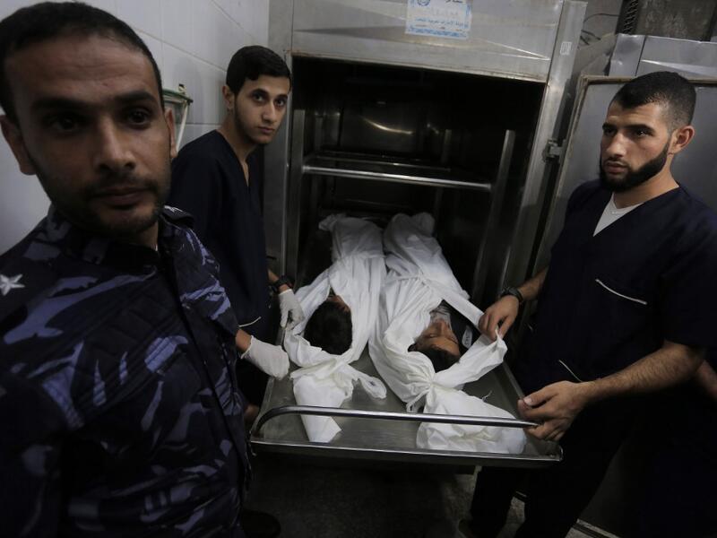 Palestinian police and morgue workers show the bodies of two of six members of the same family killed in an Israeli airstrike, at a morgue in central Gaza Strip's Deir al-Balah on November 14, 2019. Six members of the same family were killed in an Israeli airstrike on the southern Gaza Strip, the health ministry of the coastal Palestinian enclave said on November 14. The deaths bring the toll from Israeli strikes targeting Islamic Jihad militant sites to 32 since November 12, while 350 rockets have been fir