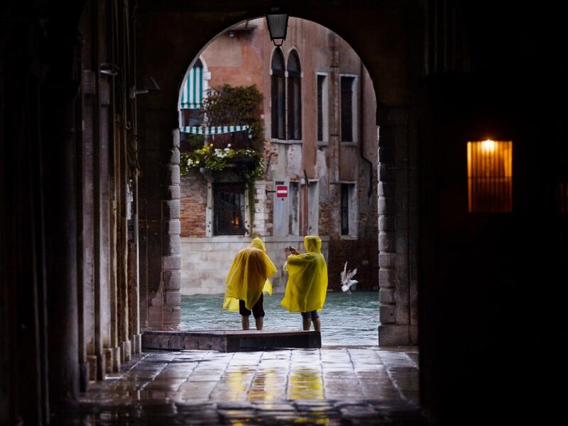 People take pictures in a street near the Rialto Bridge, on November 15, 2019 in Venice, two days after the city suffered its highest tide in 50 years. Flood-hit Venice was bracing for another exceptional high tide on November 15, as Italy declared a state of emergency for the UNESCO city where perilous deluges have caused millions of euros worth of damage. Filippo MONTEFORTE / AFP