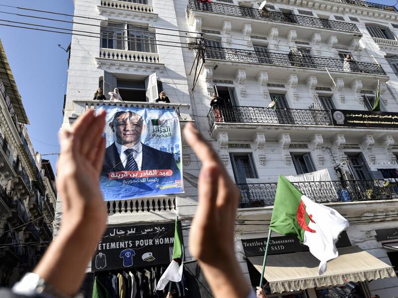A supporters of Abdelkader Bengrina, former Algerian tourism minister and presidential candidate for the El-Bina (Construction) Islamist party, applauds outside his electoral campaign headquarters in the capital Algiers on November 17, 2019. (RYAD KRAMDI / AFP)