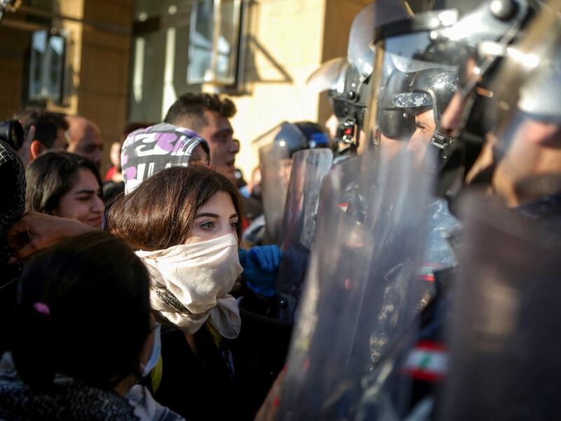 Lebanese anti-government protesters face security forces during a demonstration near the parliament headquarters in the capital Beirut's downtown district on November 19, 2019. Lebanon's parliament, besieged by protesters, said it had indefinitely postponed a session that had been due to discuss controversial draft laws. "The session has been postponed to a date to be determined later," said parliament official Adnane Daher, reading a statement in front of television cameras, citing "exceptional conditions,