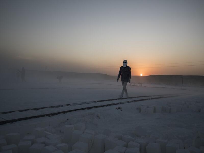 A labourer walks wearing protective gear at the "White Mountain" limestone extraction quarry site near Egypt's southern city of Minya, some 265 kilometres south of the capital, on November 13, 2019. Covered in fine white dust, labourers at the so-called "White Mountain" off Minya toil in shifts amidst brutal conditions with little workplace safety for paltry pay. They handle dangerous machinery with finesse, and shrug off the dangers of a job where a mistake can prove fatal. Khaled DESOUKI / AFP