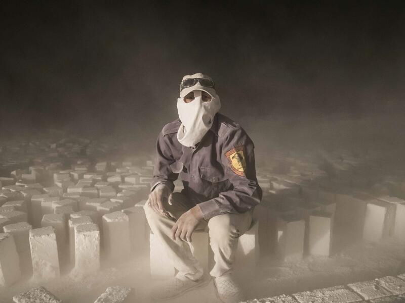 A labourer wearing protective gear poses for a picture while sitting on stone blocks while working late at night at the "White Mountain" limestone extraction quarry site near Egypt's southern city of Minya, some 265 kilometres south of the capital, on November 13, 2019. AFP