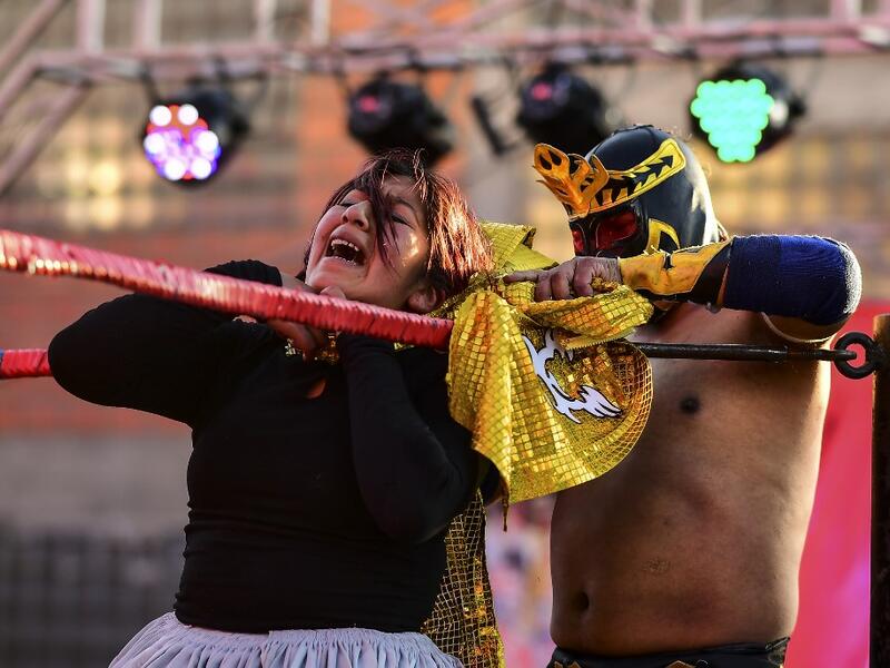 Bolivian wrestler Blanca Perez (L), aka "Katy The Beautiful", a member of the Fighting Cholitas, fights with a male wrestler at Sharks of the Ring wrestling club in El Alto, Bolivia, on November 24, 2019. After a fortnight hiatus due to anti-government protests and blockades, the Fighting Cholitas are back in the ring. The unrest was triggered by the disputed October 20 election, which Evo Morales claimed to have won and opposition groups said was rigged. Ronaldo SCHEMIDT / AFP