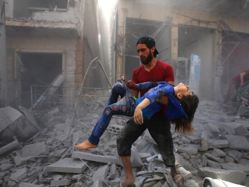 A man evacuates a young bombing casualty after a reported air strike by regime forces and their allies in the jihadist-held Syrian town of Maaret Al-Noman in the southern Idlib province, on May 26, 2019. Regime air strikes killed 12 civilians including four at a market today in a jihadist bastion in northwest Syria, a war monitor said. Abdulaziz KETAZ / AFP