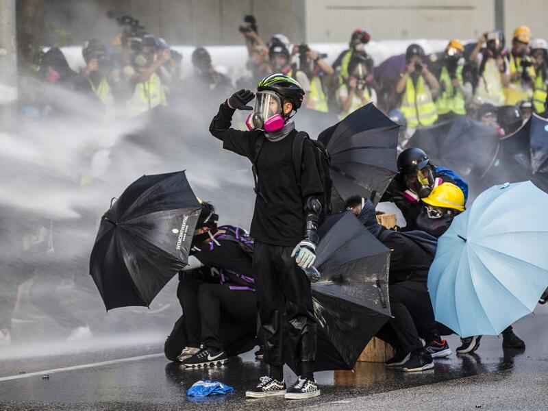 AFP PICTURES OF THE YEAR 2019 - Pro-democracy protesters react as police fire water cannons outside the government headquarters in Hong Kong on September 15, 2019. Hong Kong riot police fired tear gas and water cannons on September 15 at hardcore pro-democracy protesters hurling rocks and petrol bombs, in a return to the political chaos plaguing the city. Isaac LAWRENCE / AFP