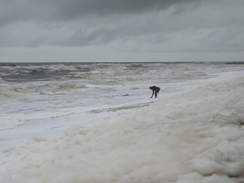 Residents play over foamy discharge, caused by pollutants, as it mixes with the surf at Marina beach in Chennai on December 1, 2019. Arun SANKAR / AFP