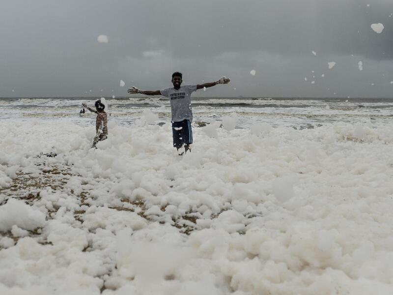 Residents play over foamy discharge, caused by pollutants, as it mixes with the surf at Marina beach in Chennai on December 1, 2019. Arun SANKAR / AFP