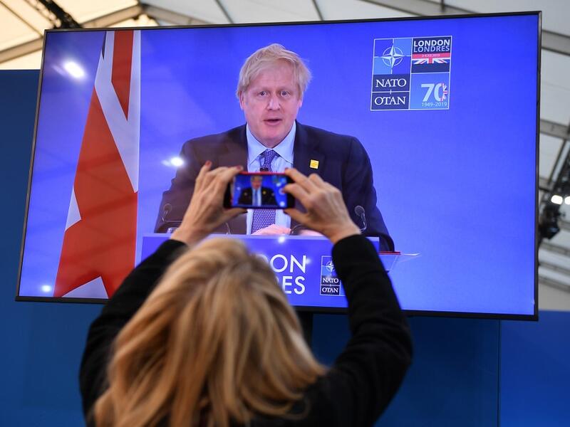 A journalist takes a picture of a television screen as Britain's Prime Minister Boris Johnson speaks during a press conference at the NATO summit at the Grove hotel in Watford, northeast of London on December 4, 2019. DANIEL LEAL-OLIVAS / AFP