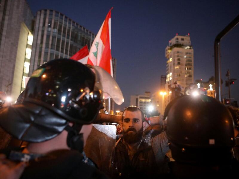 A Lebanese anti-government protester faces riot police on the eastern end of the Ring bridge that connects the western and eastern neighbourhoods of the capital Beirut on December 4, 2019. AFP