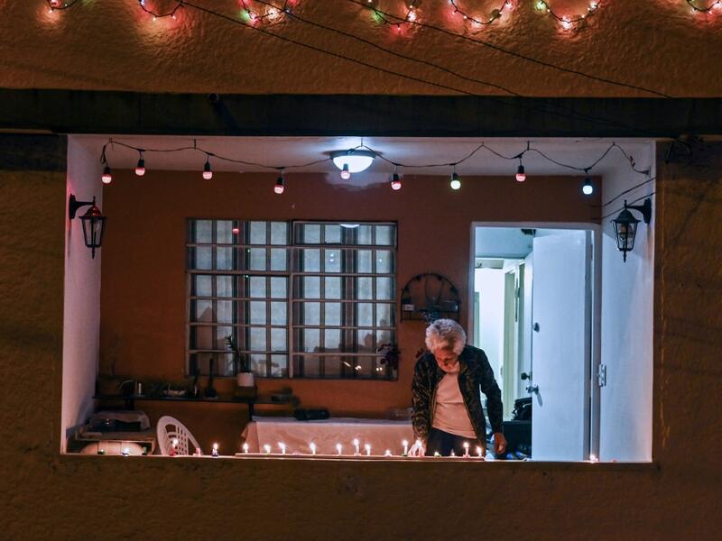 A woman lights a candle at the Comuna 13 in Medellin, Colombia, on December 7, 2019, on the Day of the Little Candles. The Day of the Little Candles is a traditional Colombian celebration which commemorates the Immaculate Conception of the Virgin Mary and marks the beginning of the Christmas season. On this day, light candles in their homes, on streets, and at cemeteries to decorate the graves of their dead. JOAQUIN SARMIENTO / AFP