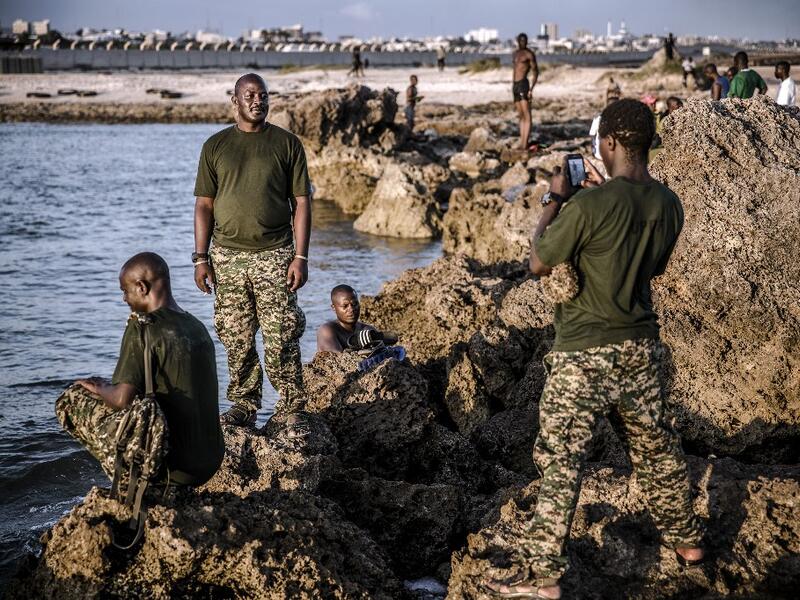 A group of UPDF (Uganda People Defence Forces) soldiers deployed in Somalia as part of the African Union peacekeeping take pictures while enjoying a day off by the beach within Mogadishu’s airport base in Mogadishu, Somalia, on December 13, 2019. LUIS TATO / AFP