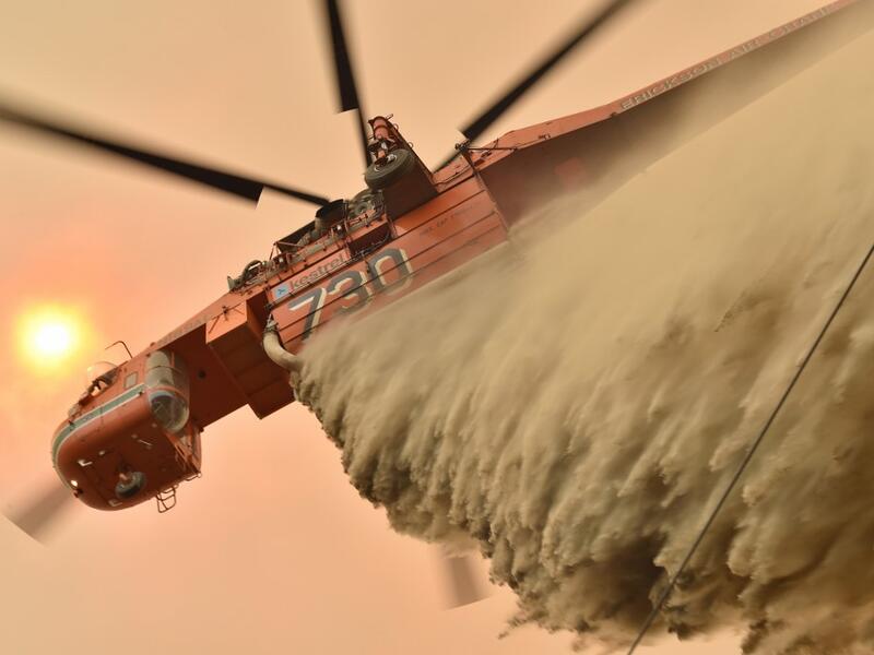 A helicopter drops fire retardent to protect a property in Balmoral, 150 kilometres southwest of Sydney on December 19, 2019. A state of emergency was declared in Australia's most populated region on December 19, as a record heat wave fanned unprecedented bushfires. PETER PARKS / AFP
