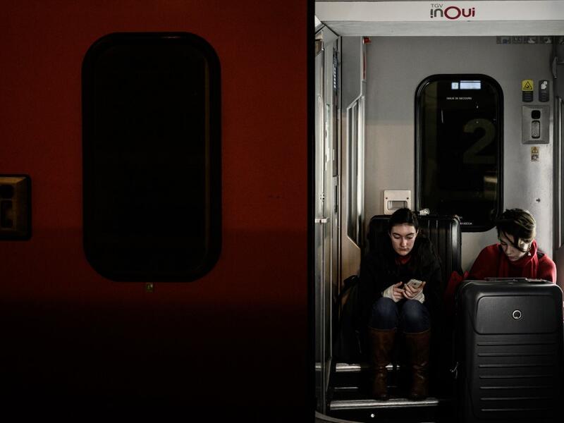 Travellers waiting for departure sit between two coaches at the Gare de Lyon railway station in Paris on December 20, 2019, on the 16th day of a nationwide multi-sector strike against the government's pensions overhaul. Philippe LOPEZ / AFP