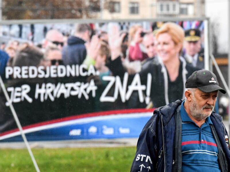 A man walks past a placard of the current Croatian President and candidate Kolinda Grabar-Kitarovic for the presidential election, from outside a window, in downtown Zagreb, December 21, 2019. Croatia voters will go to the polls on December 22, 2019 for the Croatian presidential election. Denis LOVROVIC / AFP