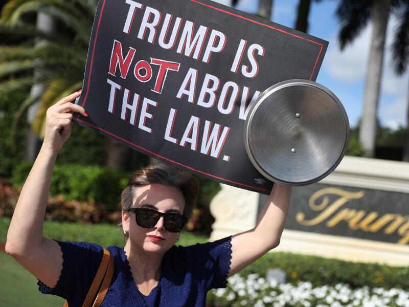 Aileen Ortega joins with other protesters outside of the Trump National Doral golf resort urging congress to impeach President Donald Trump (AFP)