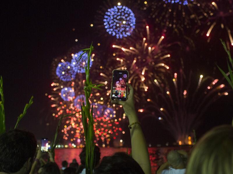 A woman takes pictures while celebrating with the traditional New Year's fireworks at Copacabana Beach in Rio de Janeiro, Brazil, on December 31, 2019. DANIEL RAMALHO / AFP