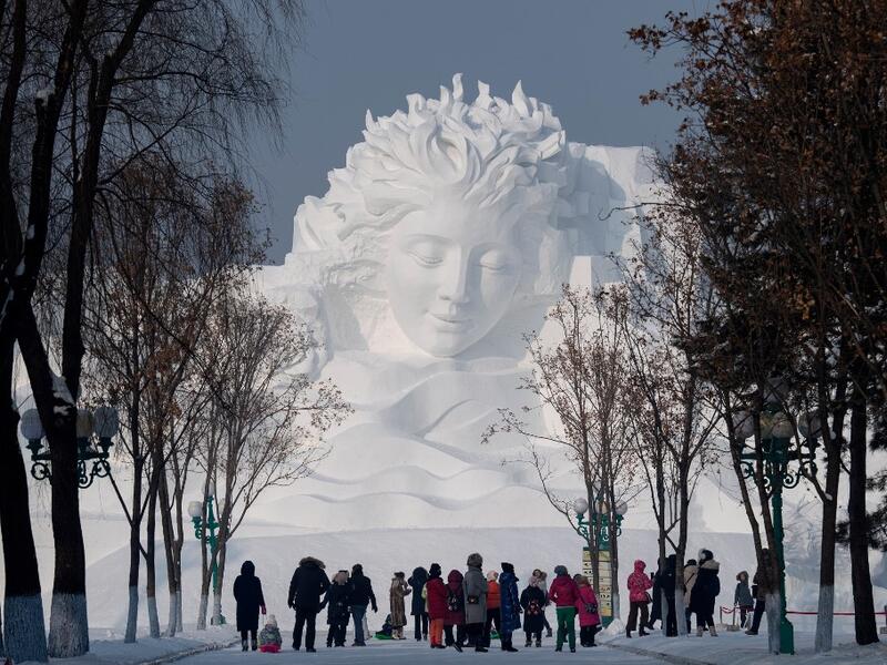 Tourists walk in front of an ice sculpture ahead of the opening of the Harbin International Ice and Snow Festival in Harbin, in China's northeast Heilongjiang province on January 4, 2020. NOEL CELIS / AFP