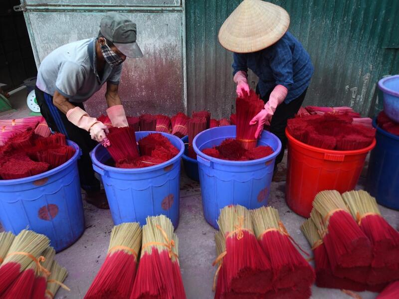 Vietnamese workers dye incense sticks in Quang Phu Cau village on the outskirts of Hanoi on January 9, 2020 ahead of the upcoming Lunar New Year celebrations, referred to in Vietnam as Tet. Nhac NGUYEN / AFP