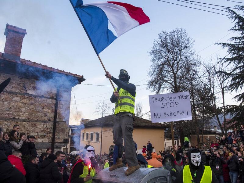 Masked revellers - one wearing a yellow vest waving a French national flag - another with a placard which reads as " enough is enough" take part with others in a carnival procession through the south-western North Macedonian village of Vevcani, on January 13, 2020. The Vevcani carnival is 1.400 years old and is held every year on the eve of the feast of Saint Basil (January 14), which also marks the beginning of the New Year according to the Julian calendar, observed by the Macedonian Orthodox Church. Rober