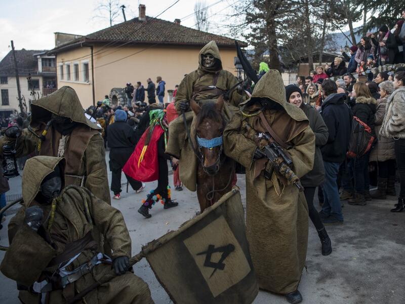 Costumed revellers sporting in their costumes a Freemason's square and compass flag and an assault rifle take part in a carnival procession through the south-western North Macedonian village of Vevcani, on January 13, 2020. The Vevcani carnival is 1,400 years old and is held every year on the eve of the feast of Saint Basil (January 14), which also marks the beginning of the New Year according to the Julian calendar, observed by the Macedonian Orthodox Church. Robert ATANASOVSKI / AFP