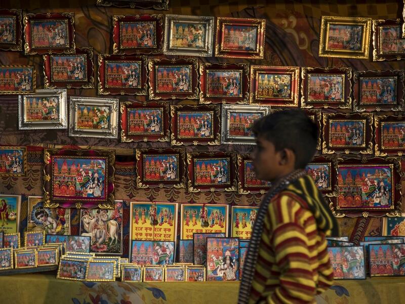 A young Hindu devotee walks past a stall selling religious images during the Gangasagar Mela, at Sagar Island, some 150 kilometres south of Kolkata on January 14, 2020. XAVIER GALIANA / AFP
