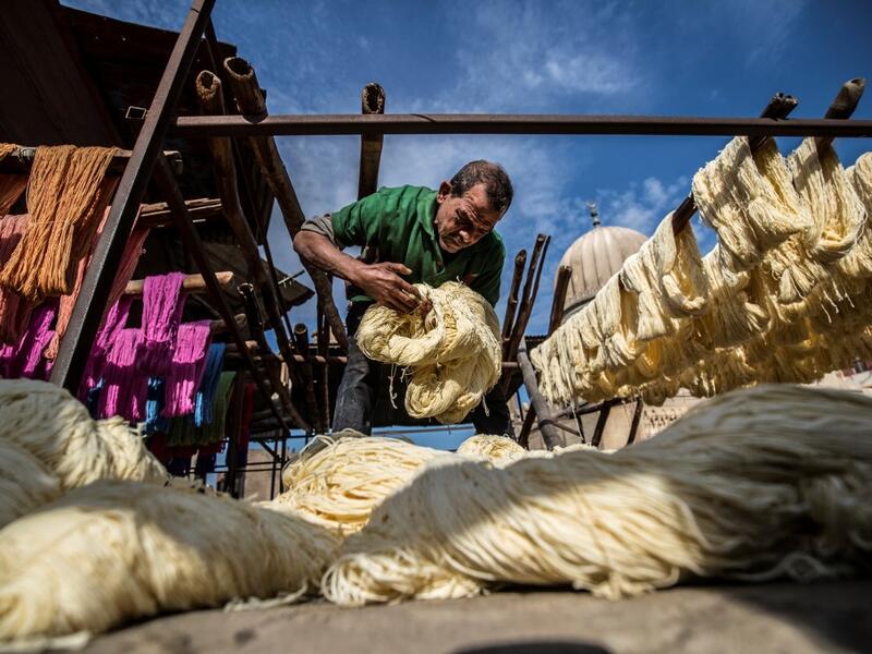 Mohamed Kamal, a 59-year-old dye worker, prepares to hang dyed yarns out to dry in the sun at a traditional hand-dying workshop in the Egyptian capital Cairo's centuries old district of Darb al-Ahmar on January 21, 2020. In Cairo's centuries-old Darb al-Ahmar district, Salama Mahmoud Salama's dye workshop is a multi-coloured den of textiles and busy workers colouring all kinds of fabrics. Khaled DESOUKI / AFP