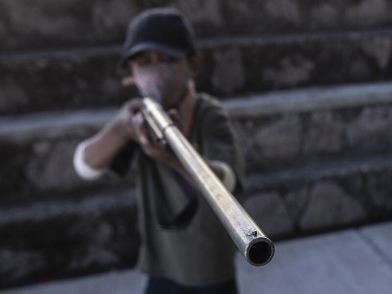 A boy aims a rifle as the Regional Coordinator of Community Authorities (CRAC-PF) community police force teaches a group of children how to use weapons, at a basketball court in the village of Ayahualtempan, Guerrero State, Mexico, on January 24, 2020. The CRAC-PF vigilante group trains children as young as five so they can protect themselves from drug-related criminal groups operating in the area. Pedro PARDO / AFP