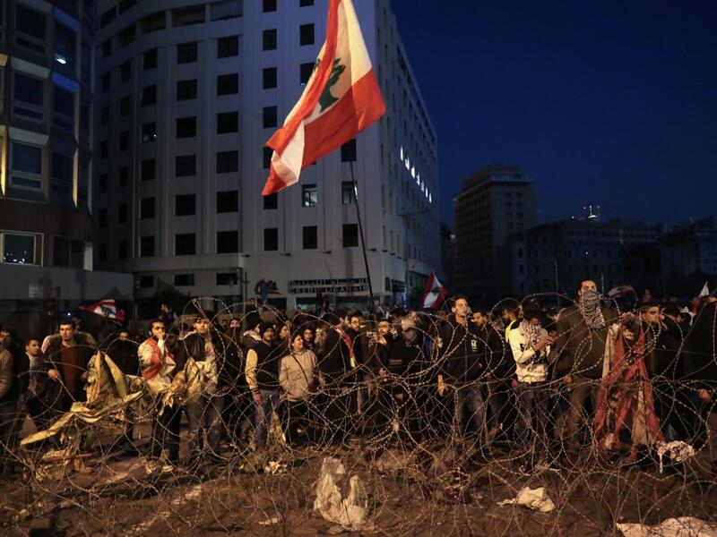 Lebanese anti-government demonstrators rally by barbed wire set by security forces to block a road leading to the government headquarters at the Grand Serail, in downtown Beirut, on January 25, 2020. ANWAR AMRO / AFP