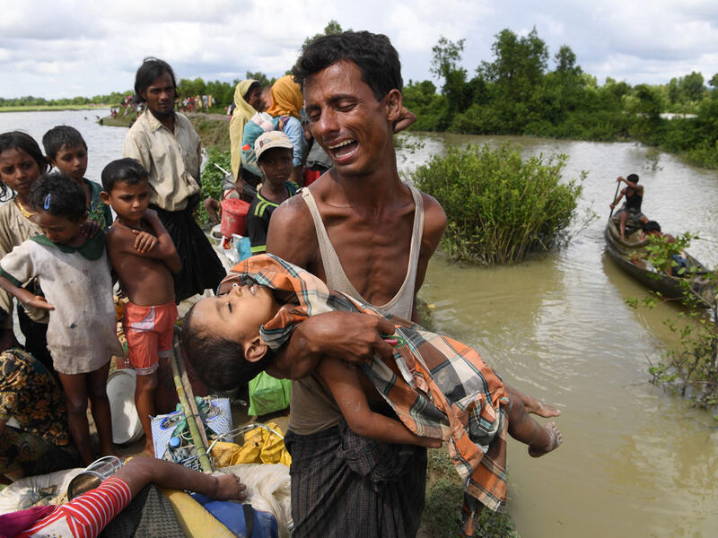 A Rohingya refugee reacts while holding his dead son after crossing the Naf river from Myanmar into Bangladesh in Whaikhyang on Oct. 9, 2017. (Indranil Mukherjee/AFP/Getty Images)