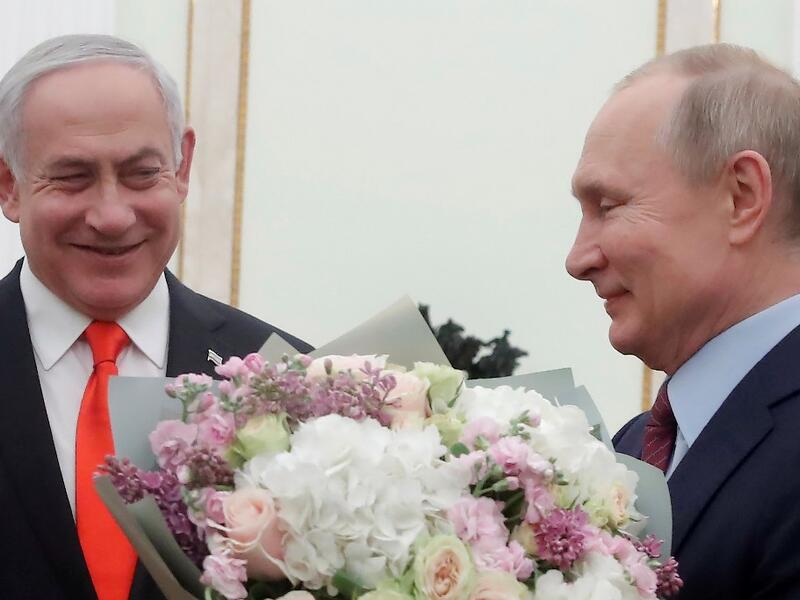Russian President Vladimir Putin holds flowers next to Israeli Prime Minister Benjamin Netanyahu as they meet at the Kremlin in Moscow on January 30, 2020. MAXIM SHEMETOV / POOL / AFP