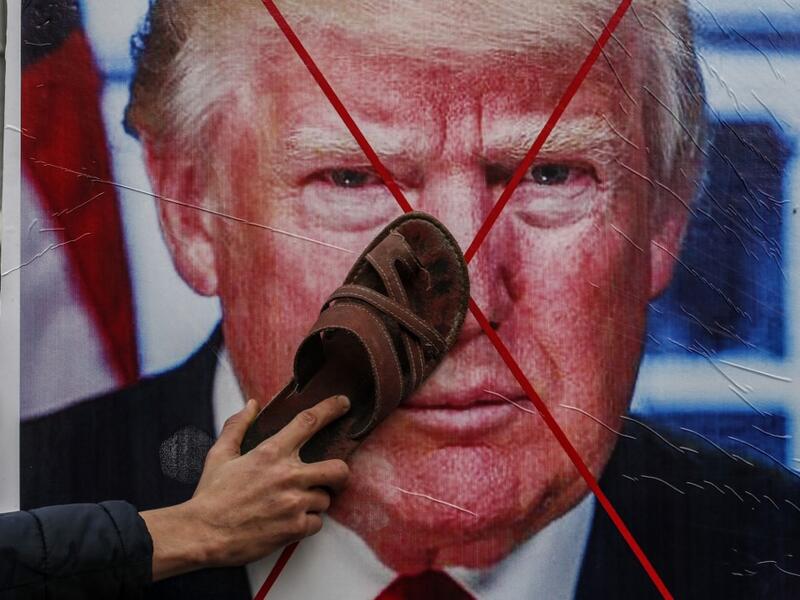 A Palestinian protester sticks his footwear on a poster depicting the face of US President Donald Trump during a demonstration against Trump's Middle East peace proposal in Khan Yunis in the southern Gaza Strip on February 3, 2020. SAID KHATIB / AFP