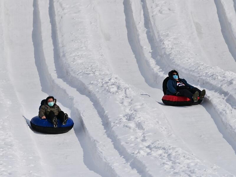People take part in snow rafting during the Sapporo Snow Festival in Sapporo on February 5, 2020. Organisers for this year's festival were forced to truck in an unprecedented amount of extra powder to build their signature sculptures after an unseasonably warm winter. CHARLY TRIBALLEAU / AFP
