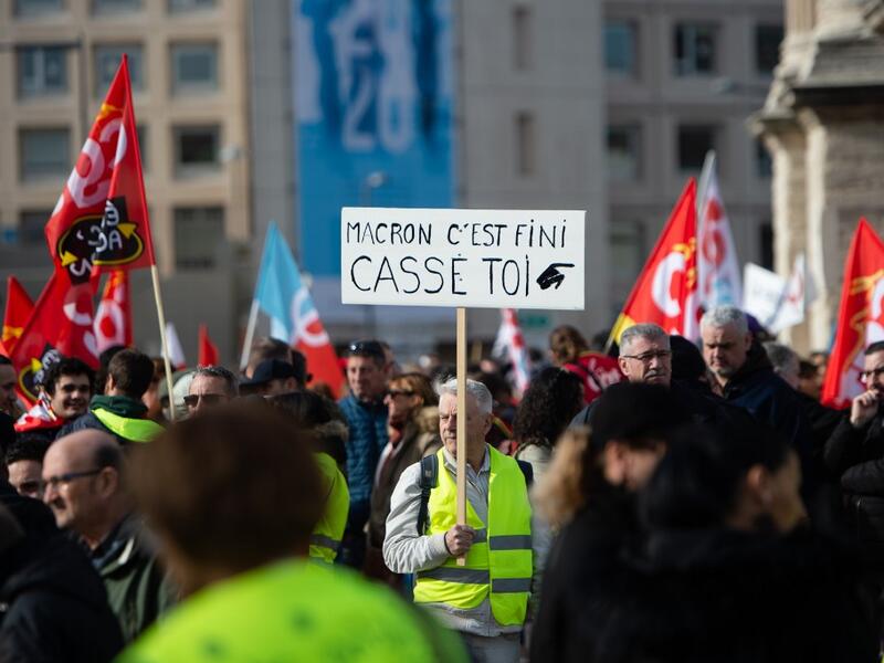 A protester wearing a yellow vest holds a sign reading "Macron, it's over, go away" as he takes part in a demonstration against the French government's plan to overhaul the country's retirement system in Marseille, southeastern France, on February 6, 2020. CLEMENT MAHOUDEAU / AFP