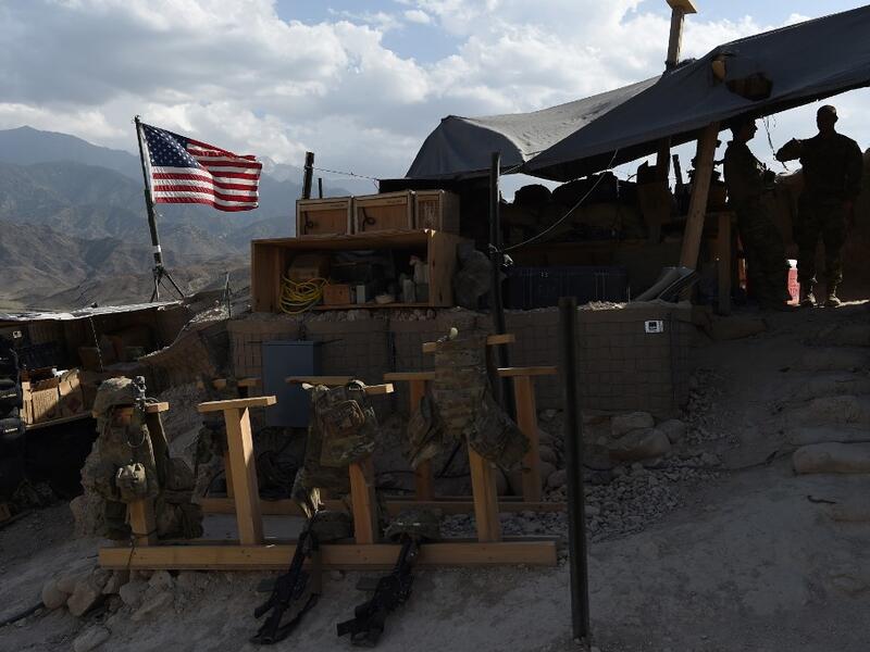 In this file photograph taken on July 7, 2018, US Army soldiers from NATO look on as U.S. flag flies at a checkpoint during a patrol against Islamic State militants at the Deh Bala district in the eastern province of Nangarhar Province. Two American troops were killed and six others wounded when an Afghan soldier armed with a machine gun opened fire, the US military confirmed on February 9. WAKIL KOHSAR / AFP