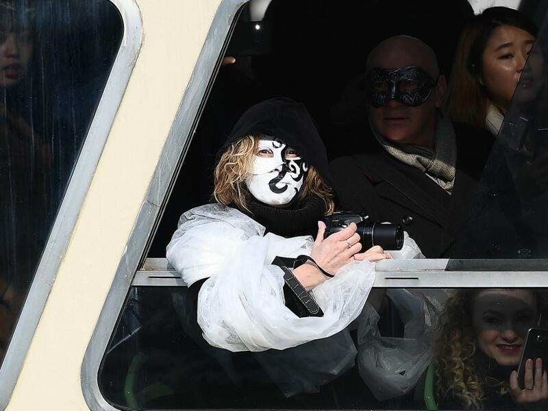 A masked reveller looks on aboard a ferry on the Grand Canal during the traditional regatta which officially opens the Carnival in Venice, on February 09, 2020. The Venice's carnival takes place until February 25, 2020. Vincenzo PINTO / AFP